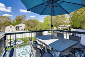Une terrasse extérieure couverte, dotée d’une table et de chaises, d’une piscine et offrant une vue sur les maisons voisines.