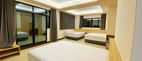 A modern hotel room with a large bed, a desk, and a sliding glass door leading to a balcony.
