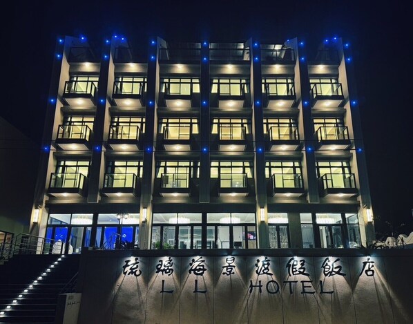 A multi-story hotel with illuminated windows and a sign in Chinese characters.