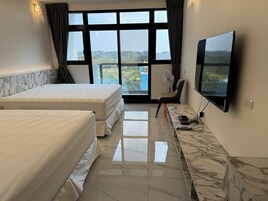 Habitación de hotel con dos camas, un escritorio de mármol, televisión y vistas al exterior.