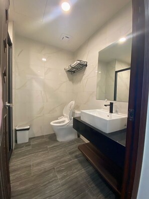 A modern bathroom with a toilet, sink, and mirror. - L.L Hotel (Liuqiu)