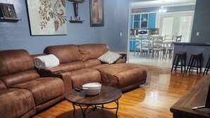 Un salon avec un canapé en cuir marron, une table basse en bois et un ventilateur de plafond.
