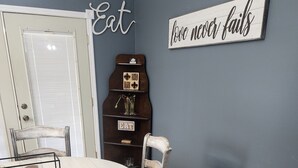 Un espace repas comprenant une table ronde, des chaises et un mur orné de panneaux décoratifs.