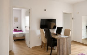 Una habitación con cama, escritorio con silla, televisor y armario.