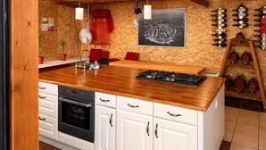 Eine Küche mit weißen Schränken, einer Holz Arbeitsplatte, einem Gasherd und einem roten Stuhl.
