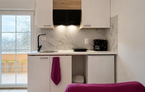 Una cocina compacta con microondas integrado, cafetera y refrigerador pequeño.