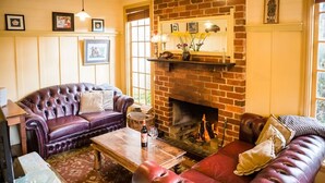 A cozy living room with a brick fireplace, leather sofas, and a coffee table.