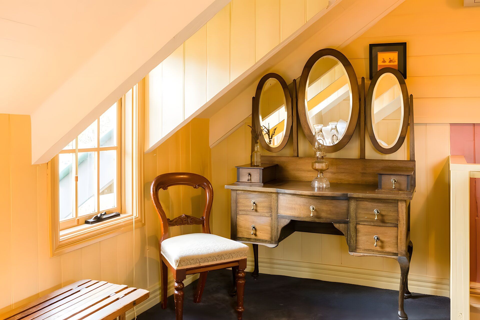 Een kamer met een houten wastafel, een stoel en een bankje.