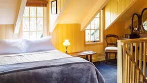 A bedroom with a bed, a nightstand, a chair, a desk, and a window.