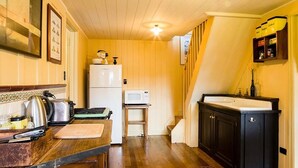 A compact kitchen with wooden cabinets, a white refrigerator, a microwave, and a sink.