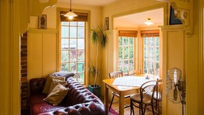 A cozy room with a leather sofa, a dining table, and chairs.