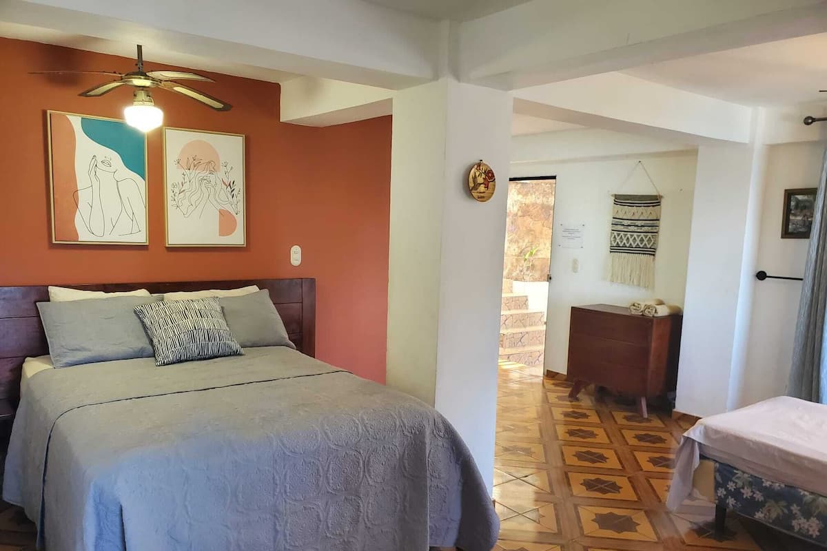 Un dormitorio con cama, cómoda y ventilador de techo.