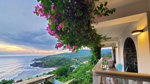 Un balcón con vista al océano y un paisaje montañoso.