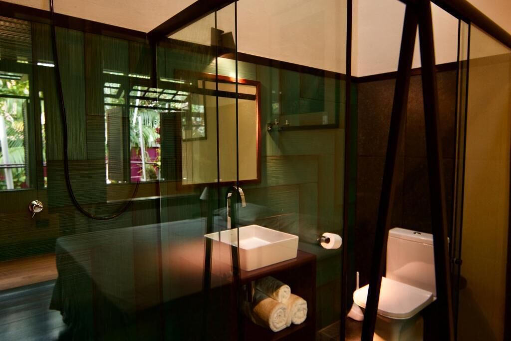 A modern bathroom with a glass partition, a white sink, a mirror, and a toilet.