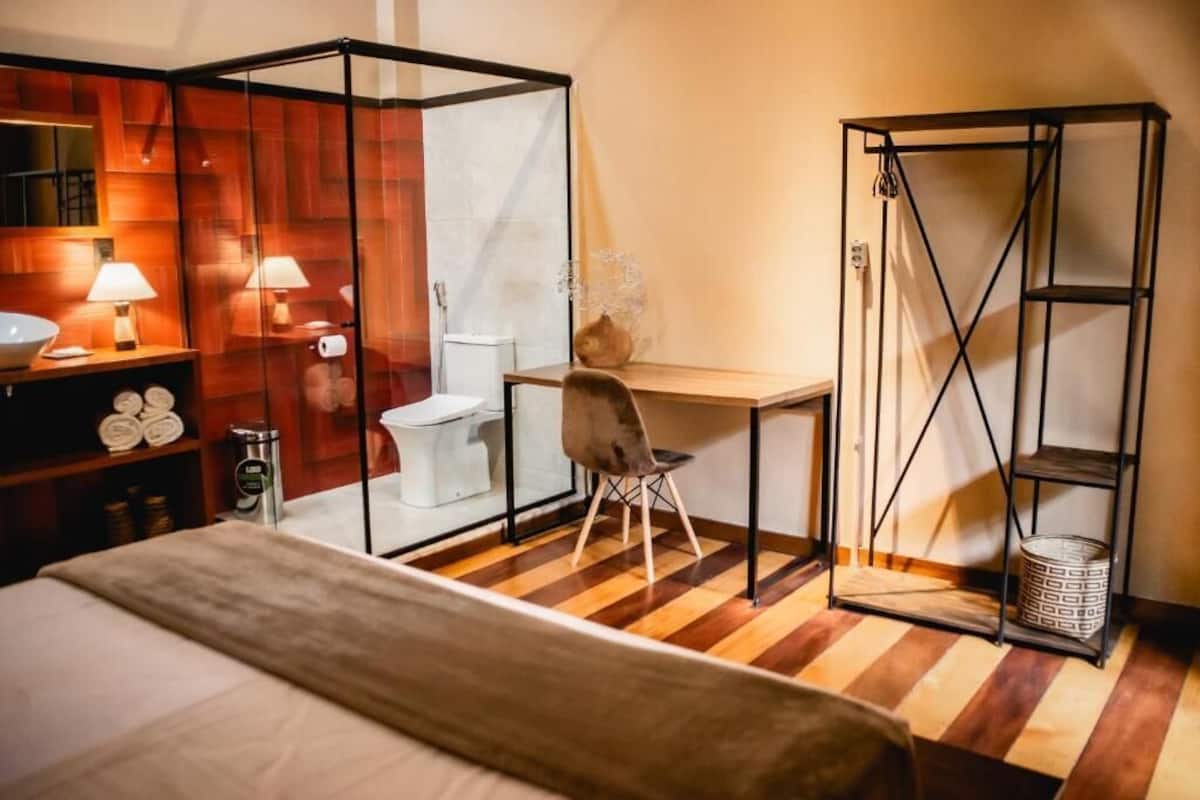 Una habitación con cama, escritorio, silla, inodoro y zona de ducha.
