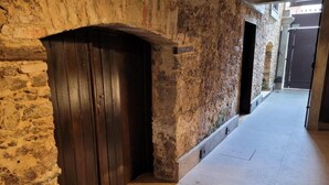 A corridor with stone walls, a wooden door, and a tiled floor. - Cas'Amazonia Brasil (Belém)