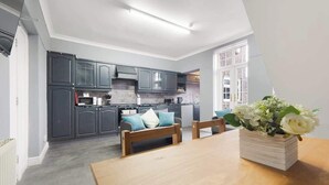 Una cocina moderna con armarios oscuros, una mesa de comedor de madera y un florero.