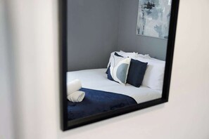 A neatly made bed with white and dark blue bedding, a dark blue throw blanket, and a white pillow. - 4BR Mitchell Street Apartment | Sleeps 6 by Stay With Us (South Moor)