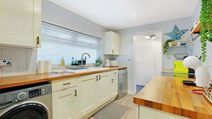 A modern kitchen with a washing machine, wooden countertop, and a star decoration on the wall. - Coastal 3-Bed Home for Families & Contractors (Redcar and Cleveland)