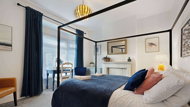 A bedroom with a four-poster bed, a desk, a chair, and a fireplace. - Coastal 3-Bed Home for Families & Contractors (Redcar and Cleveland)