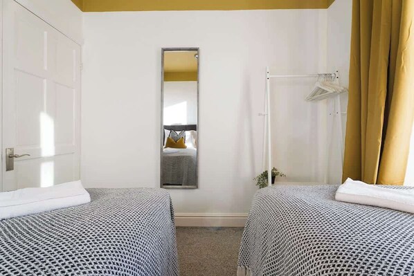Bright and comfortable, the second bedroom features two single beds dressed in soft linen. A large window allows natural light to fill the space, creating a pleasant and relaxing setting. - Norton 2BR Apartment | Sleeps 4 by Stay With Us (Norton)