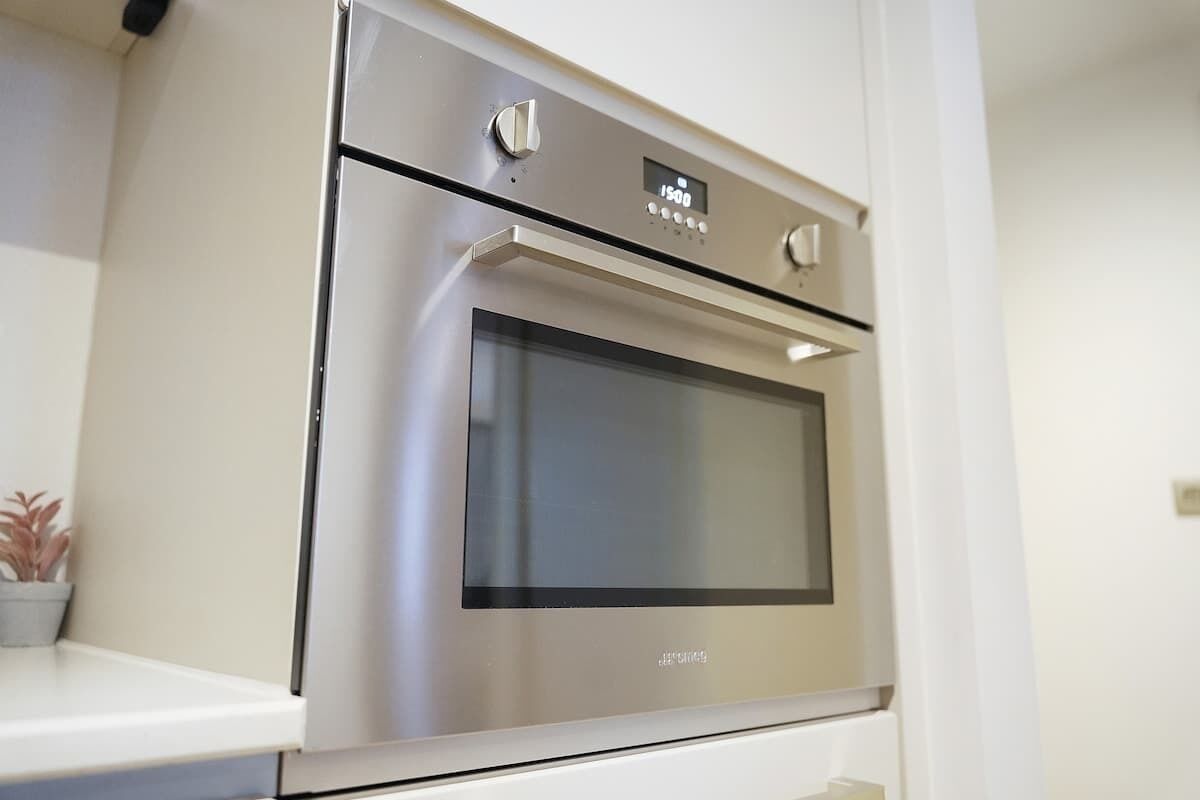 A stainless steel oven with a digital display, integrated into a kitchen counter.
