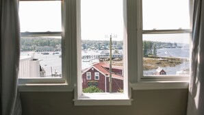 Blick aus einem Fenster auf ein Ufergebiet mit Gebäuden und einem Steg.