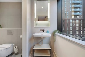A modern bathroom with a white sink, mirror, and toilet. - Modern 2-Bed Apartment | Spa & Gym | Central (Greater Manchester)