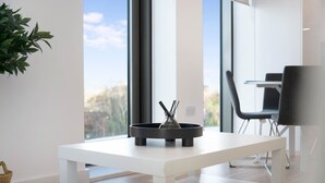 A modern room with a white table, a black object on it, and a view through large windows. - Manchester 2BR Apartment w/Super Fast WI-FI ! (Greater Manchester)