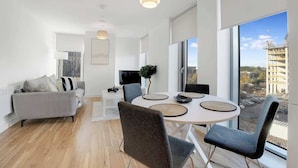 A modern living room with a sofa, dining table, chairs, and a TV. - Manchester 2BR Apartment w/Super Fast WI-FI ! (Greater Manchester)