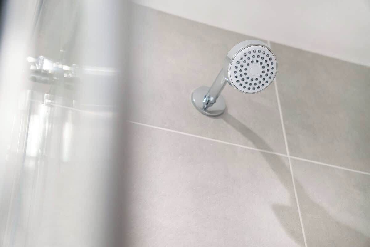 A showerhead mounted on a tiled wall.