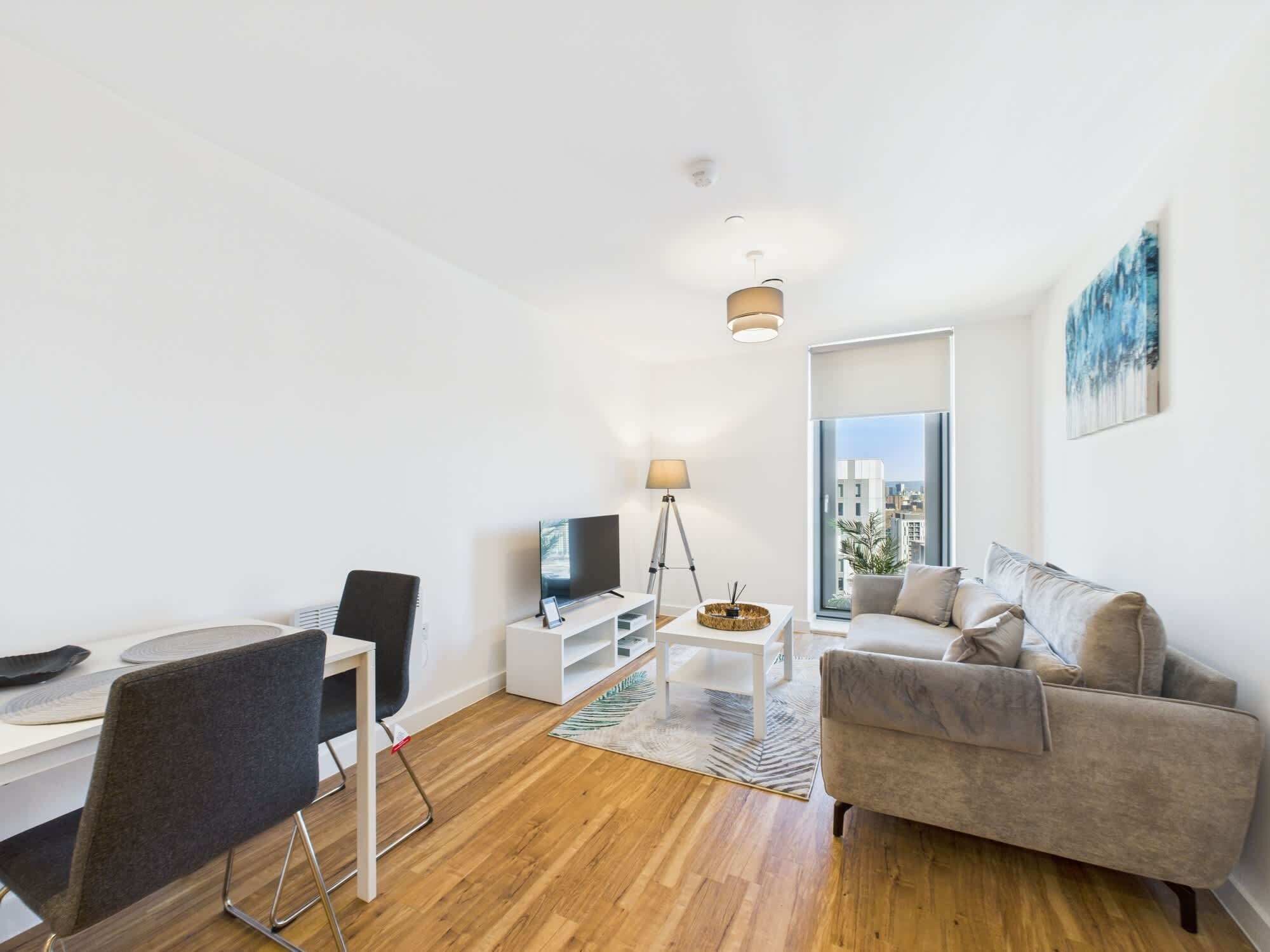 Uma sala de estar moderna com sofá, televisão, mesa de jantar e abajur.