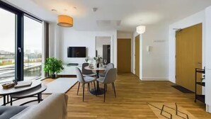 A modern interior with a dining area, a sofa, and a TV. - 2 Bed Flat Near City Centre with Free Parking (Stretford)