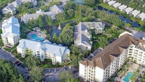 Vista aérea de uma área residencial com vários edifícios, uma grande massa de água e uma piscina.
