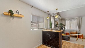 Un salon moderne doté d’un îlot de cuisine en marbre, de planchers en bois et d’un coin salon intégré.