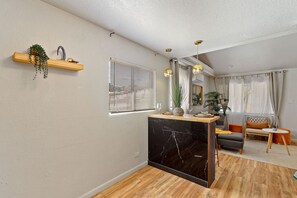 A modern living room with a marble kitchen island, wooden flooring, and a built-in seating area. - Medical Stay 2BR | Central El Paso Near Hospitals (El Paso)