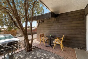 Un espace extérieur aménagé avec une table et des chaises, un arbre et une voiture garée.