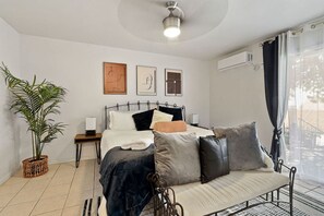 Une chambre à coucher avec un lit, des tables de chevet, une plante en pot et des œuvres d’art accrochées au mur.