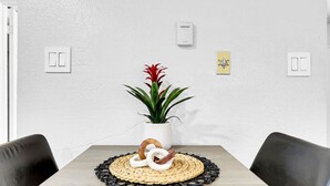 Une table à manger agrémentée d’un set de table en fibres tressées, d’une plante en pot et d’un objet décoratif.