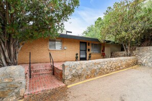 Una casa a due piani in mattoni con un muro di sostegno in pietra, un portico e una piccola finestra.