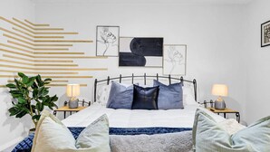 Une chambre à coucher moderne, avec un lit, des tables de chevet et des œuvres d’art murales.