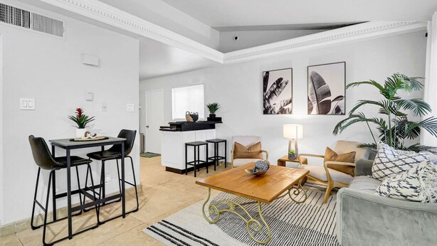 Un salon moderne avec un canapé, une table basse et un coin repas avec des chaises.