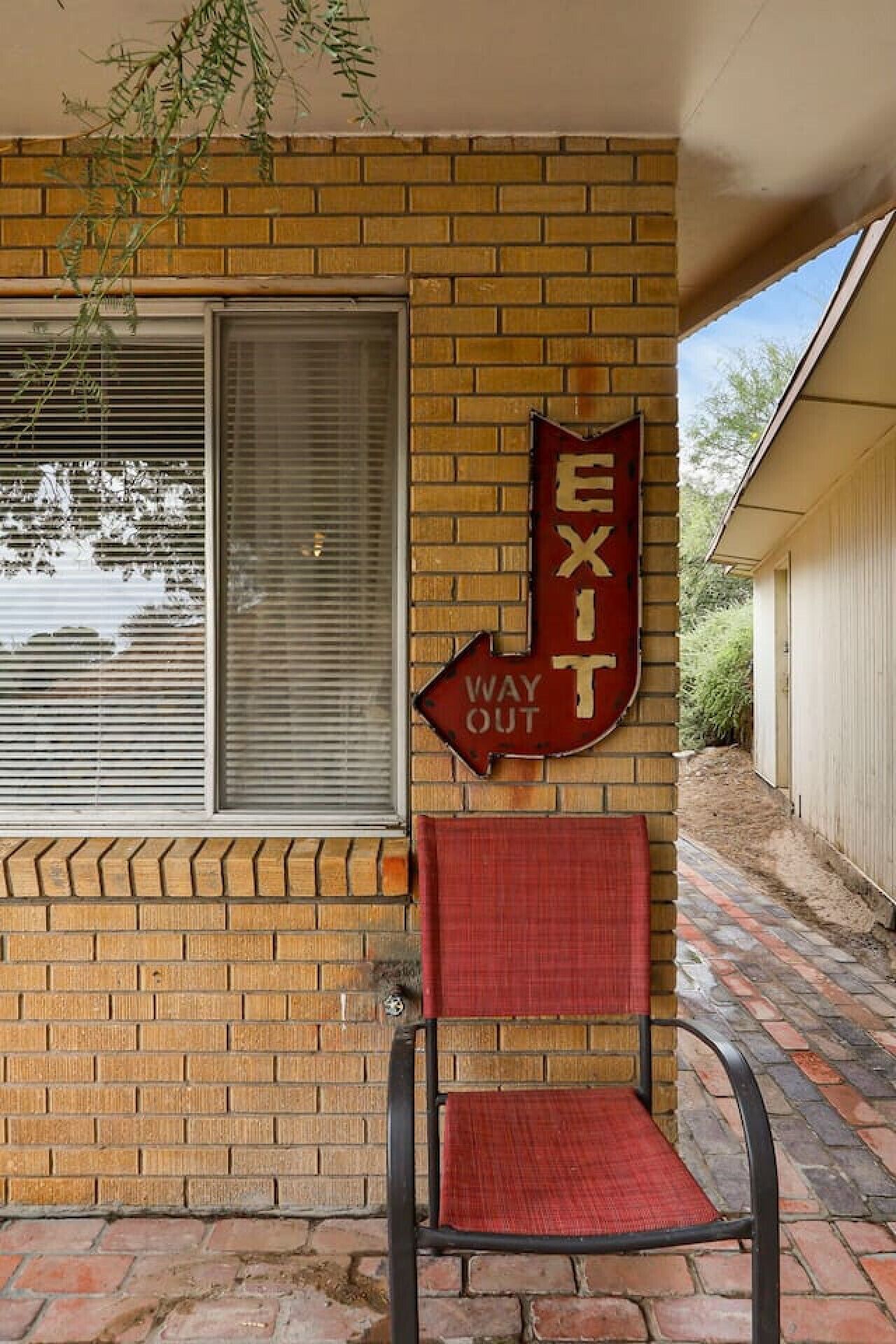 Un bâtiment en briques avec une enseigne de sortie rouge et une chaise devant.