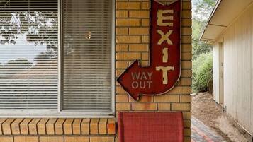 A brick building with a red exit sign and a chair in front.