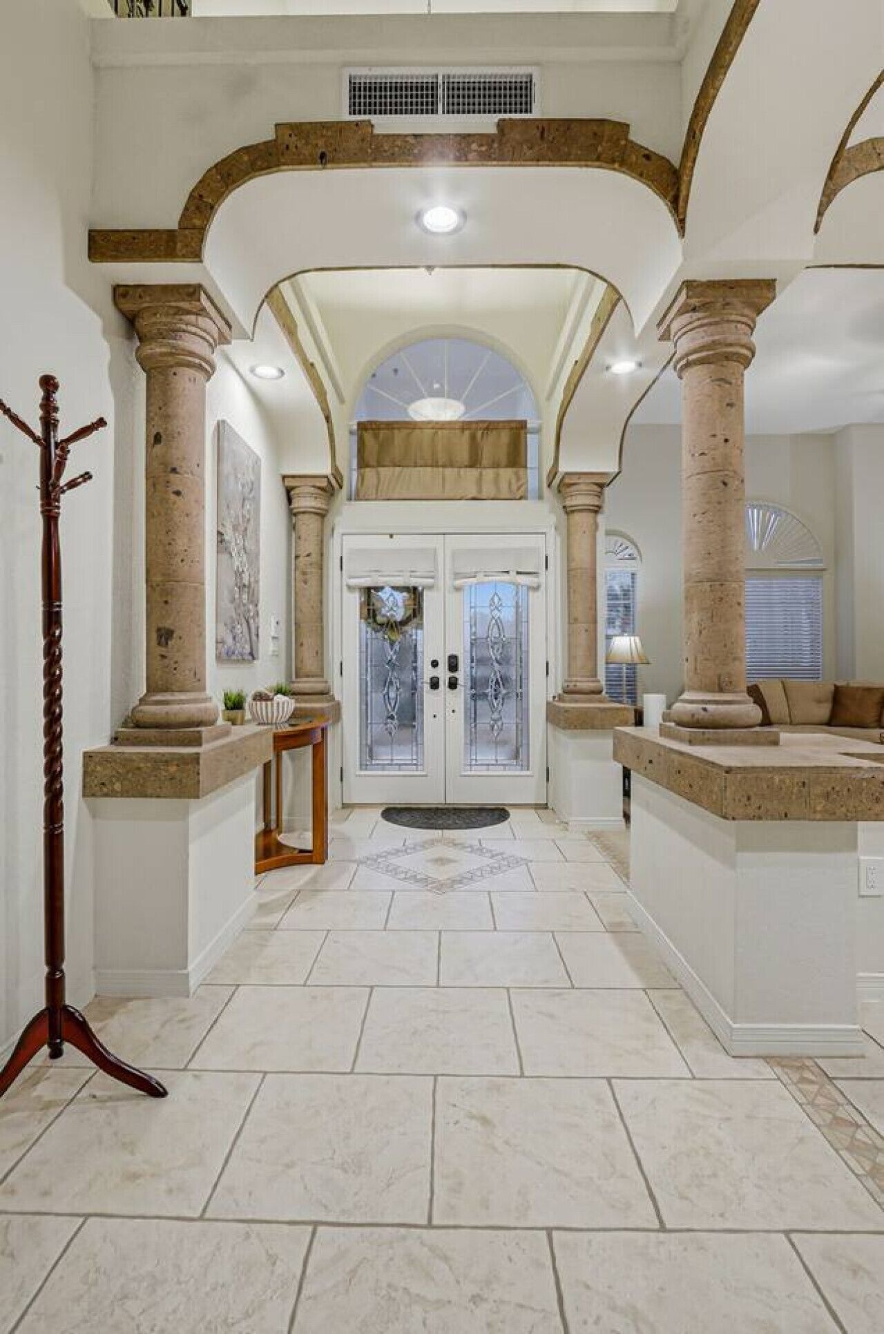 A spacious foyer with a high ceiling, large columns, and a double door entrance.