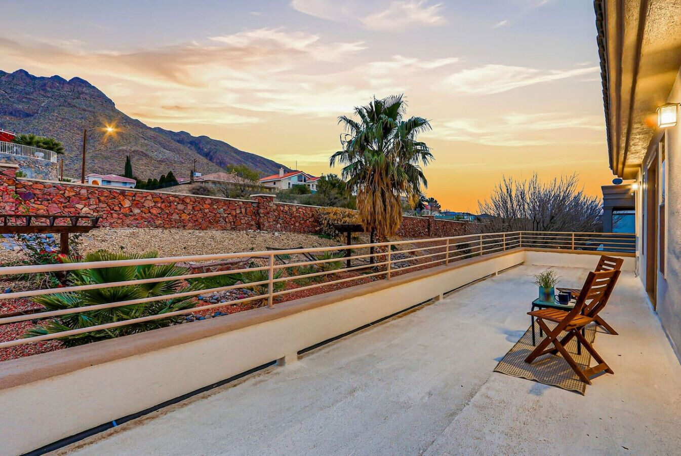 Ein Balkon mit Blick auf eine gebirgige Landschaft, einer Palme und einem Tisch mit Stühlen.