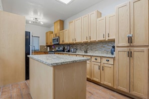 Una cocina con armarios de madera, encimeras de granito y microondas integrado.
