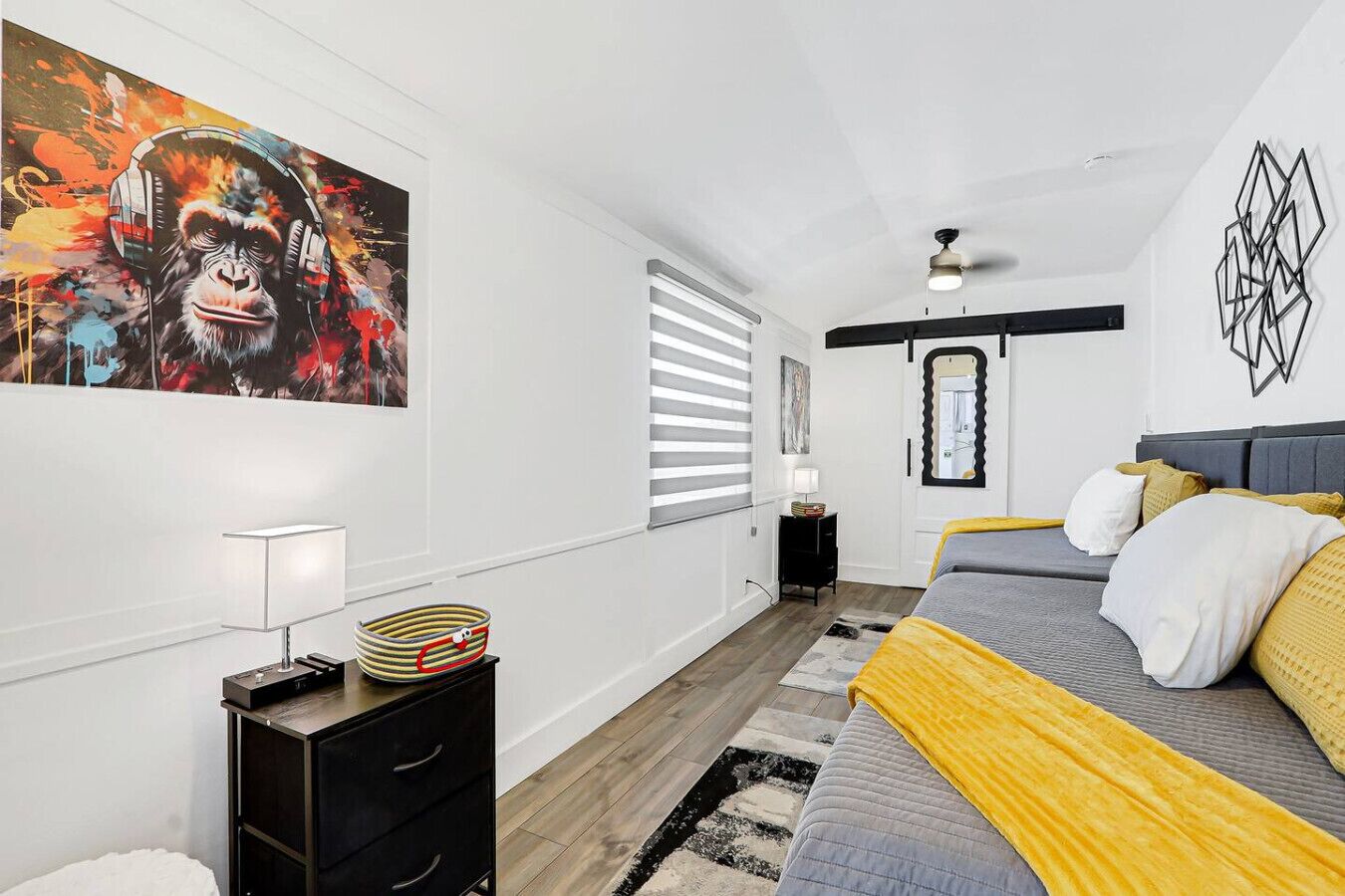 A modern bedroom with a large bed, a nightstand, a lamp, and a painting on the wall.