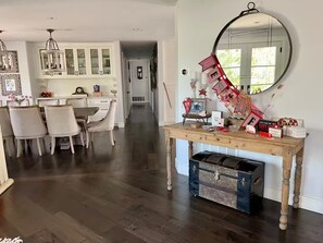 Ein Essbereich mit Holztisch und -stühlen, eine Küche mit weißen Schränken und ein Spiegel an der Wand.