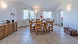 A spacious dining area with a round table and multiple chairs, a wooden cabinet with drawers, and a large window providing natural light. - Stunning home in Peruski (Peruski)